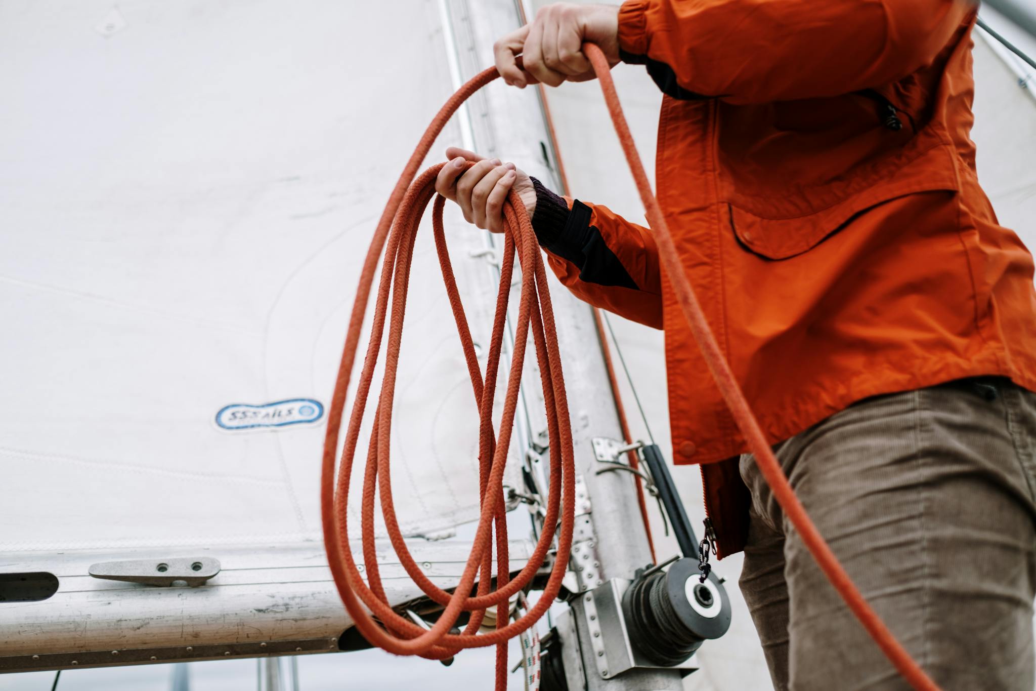 Person in Orange Jacket Holding Brown Hose